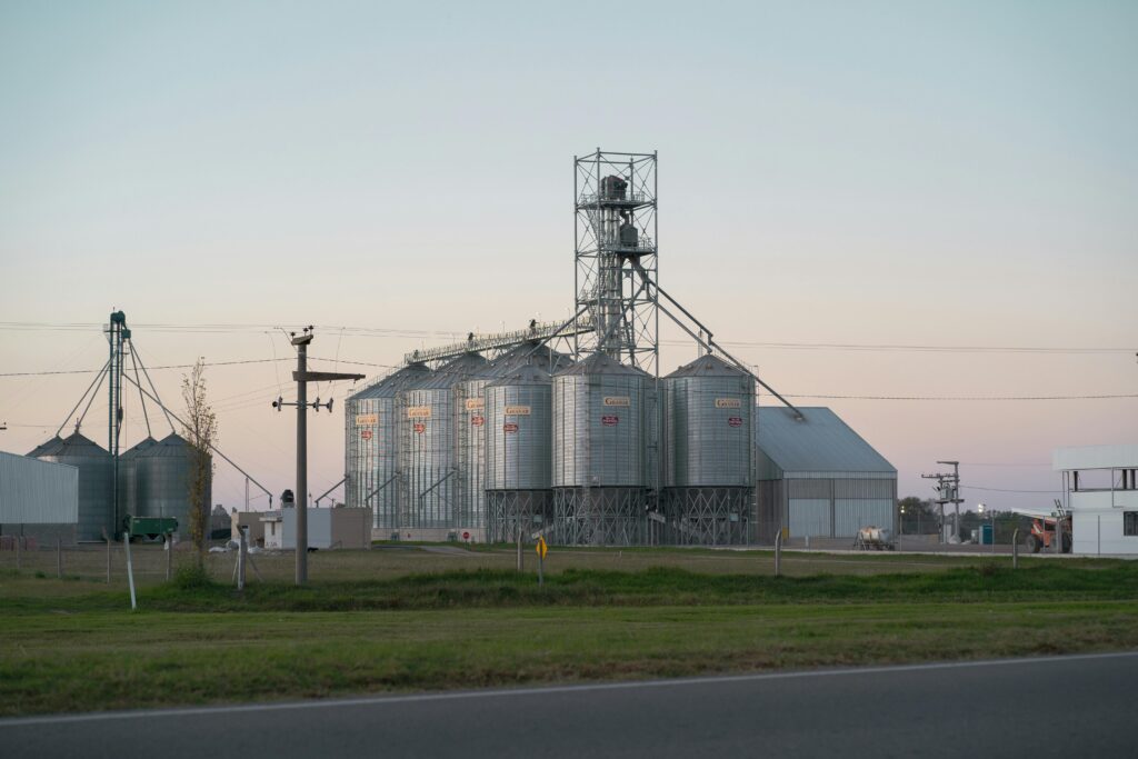 Metal grain silos alongside rural road in Hernando, Córdoba, Argentina at dusk.