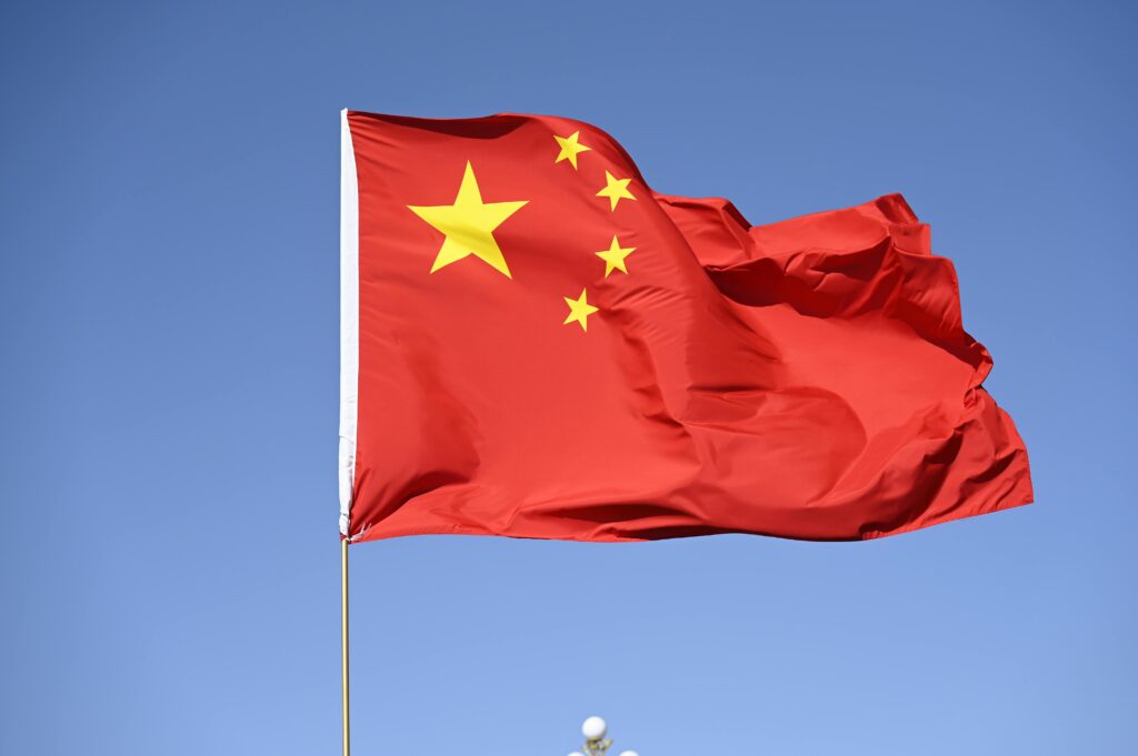 Chinese national flag flying high against a clear blue sky, symbolizing unity and pride.